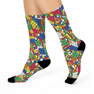 May include: A pair of colorful socks with a pattern of Rubik's Cubes. The socks are black at the toe and heel.
