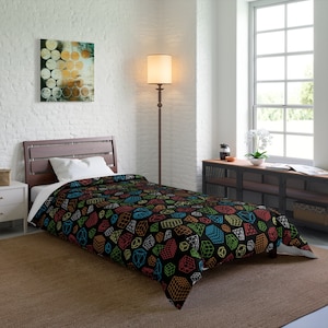 May include: A black twin-size comforter featuring a geometric cube pattern in various colors, including red, green, blue, and yellow. The cubes are outlined in white and scattered across the comforter.