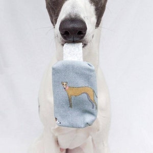 May include: A black and white Greyhound dog with a blue and white patterned fabric toy in its mouth. The toy has a picture of a brown Greyhound on it.