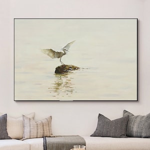 Puede incluir: Una pintura de una garceta blanca con las alas extendidas de pie sobre una roca en un cuerpo de agua. El agua es de color azul claro y el cielo es de color gris claro.