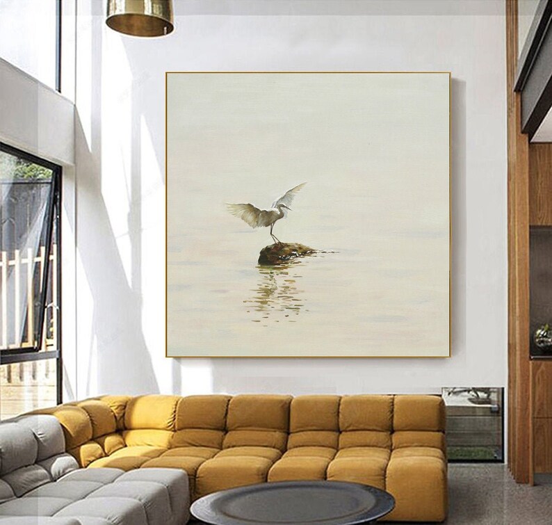 Puede incluir: Una pintura de acuarela de un p&aacute;jaro blanco con las alas extendidas de pie sobre una roca en un cuerpo de agua. El fondo es de color beige claro.