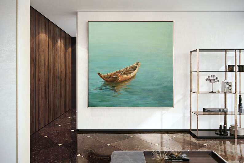 May include: A painting of a wooden boat floating on a calm, blue-green body of water. The boat is brown and has a light brown interior. The water is a light blue-green color and reflects the sky. The painting is framed in a simple, white frame.