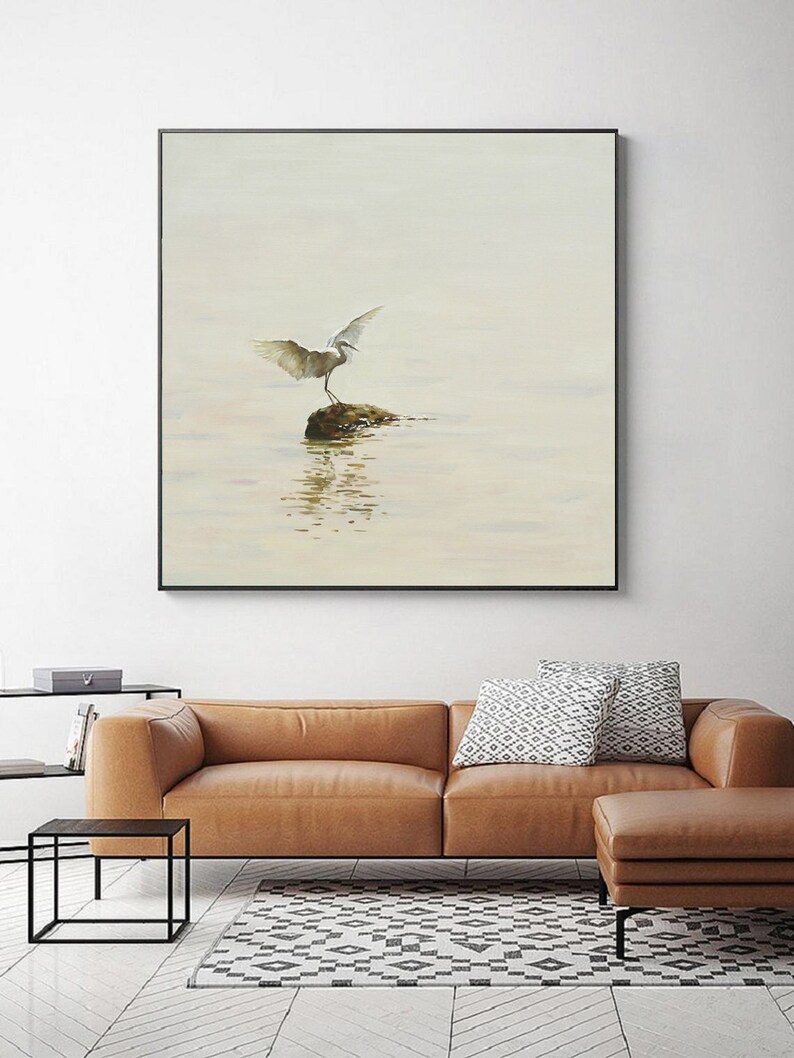Puede incluir: Una pintura de acuarela de un p&aacute;jaro blanco con las alas extendidas de pie sobre una roca en un cuerpo de agua. El fondo es de color azul claro y el agua es de color azul claro con un toque de verde.