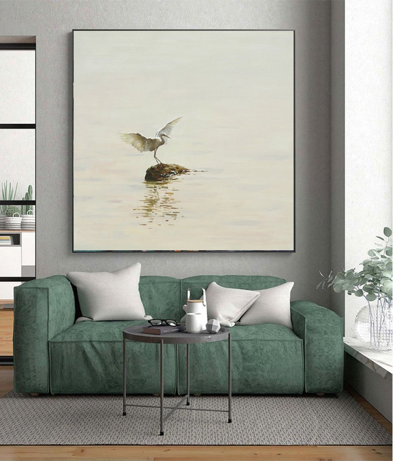 Puede incluir: Una pintura de un p&aacute;jaro blanco con las alas extendidas de pie sobre una roca en un cuerpo de agua. El fondo es azul claro y blanco.