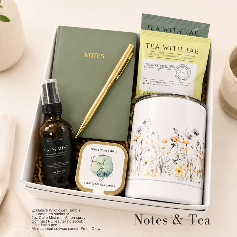 Puede incluir: Una caja de regalo que contiene un cuaderno verde salvia con la palabra NOTES, un bol&iacute;grafo dorado, dos bolsitas de t&eacute; verde al jazm&iacute;n Tea With Tae, un frasco de vidrio &aacute;mbar de 59 ml de spray Calm Mist, una vela de soja Fresh Glow y un vaso blanco.