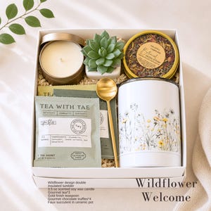Puede incluir: Una caja de regalo que contiene un vaso t&eacute;rmico blanco con estampado de flores silvestres, una vela de cera de soja de 100g en lata dorada, una cucharilla dorada, una suculenta artificial en maceta, vapor facial bot&aacute;nico y tres bolsitas de t&eacute;.
