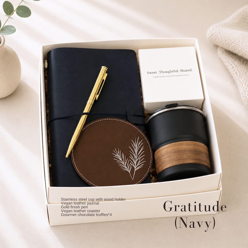 K&ouml;nnte beinhalten: Eine marineblaue Geschenkbox mit der Aufschrift "Gratitude (Navy)" enth&auml;lt ein marineblaues Notizbuch, einen goldenen Stift, einen braunen Untersetzer, eine schwarze Tasse mit Holzhalter und eine kleine wei&szlig;e Schachtel. Der Untersetzer hat ein wei&szlig;es Blattdesign.