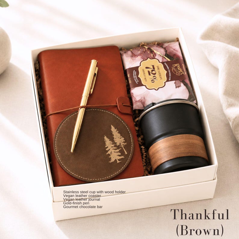 Puede incluir: Una caja de regalo "Agradecido (Marr&oacute;n)" contiene un diario de cuero vegano marr&oacute;n, un bol&iacute;grafo dorado, un posavasos con dise&ntilde;o de &aacute;rbol, una taza de acero inoxidable negra con soporte de madera y una barra de chocolate gourmet.