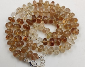 May include: A brown and clear gemstone necklace with a silver clasp and a silver pendant with the word "ELIZABETH" on it.