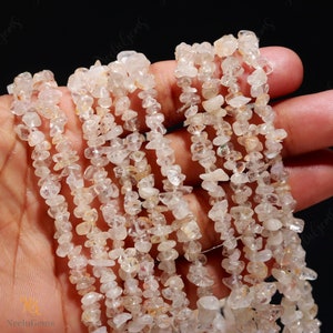 May include: A strand of clear quartz chip beads. The beads are small and irregular in shape, with a translucent appearance. The beads are strung on a thin wire.