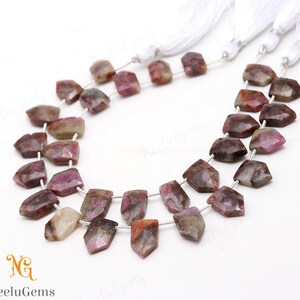 May include: A strand of pink and brown gemstone beads with a faceted, irregular shape. The beads are strung on silver wire and have a natural, rustic look.