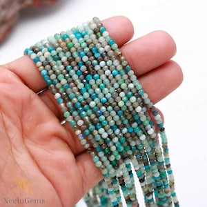 May include: A strand of blue and green gemstone beads. The beads are faceted and have a variety of shades of blue and green. The beads are strung on a clear thread and are approximately 2 mm in diameter.