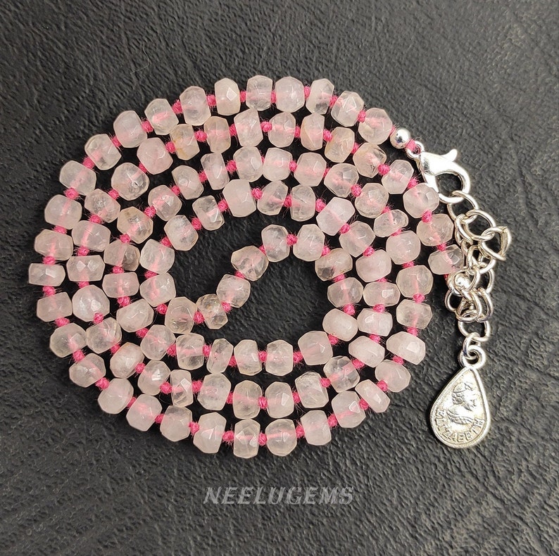 May include: A pink rose quartz necklace with faceted beads strung on pink thread. The necklace has a silver clasp and a small silver charm.