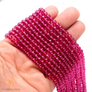 Puede incluir: Una hebra de cuentas de piedras preciosas facetadas de color rojo intenso. Las cuentas son redondas y tienen un acabado liso y pulido. Las cuentas están enhebradas en un hilo transparente y están listas para ser utilizadas en la elaboración de joyas.