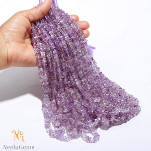 Könnte beinhalten: Eine Strähne aus hellvioletten Amethyst-Edelsteinkugeln. Die Kugeln sind facettiert und haben eine leicht unregelmäßige Form. Die Strähne ist etwa 45 cm lang.