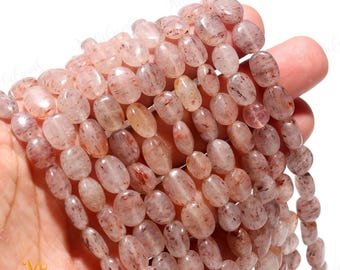 May include: A strand of translucent, oval-shaped beads with red and brown inclusions. The beads are made of natural gemstone and are strung on a clear thread.