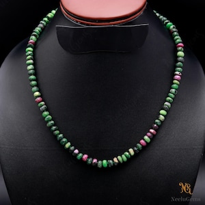 May include: A green and pink gemstone necklace with round beads. The necklace is made of natural gemstones and is strung on a silver chain.