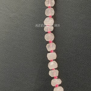 May include: A strand of faceted, clear pink quartz beads strung on pink thread. The beads are approximately 6mm in diameter.