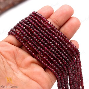 May include: A strand of deep red garnet beads, faceted and strung together. The beads are small and uniform in size, creating a smooth and elegant look.