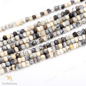 May include: A strand of white, gray, and brown gemstone beads. The beads are faceted and have a speckled pattern. The beads are strung on a clear thread.