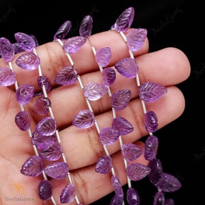 May include: A strand of purple amethyst gemstone beads, carved in the shape of leaves, strung on silver wire.