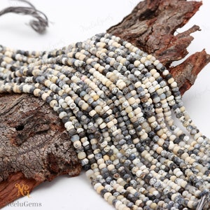 May include: A strand of white and gray speckled gemstone beads. The beads are round and have a smooth, polished finish. The beads are strung on a clear thread and are ready to be used for jewelry making.