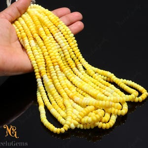 May include: Strands of yellow gemstone beads. The beads are small, round, and have a slightly irregular shape. The color varies from pale yellow to a deeper, more saturated yellow. The beads are strung together, forming multiple strands.