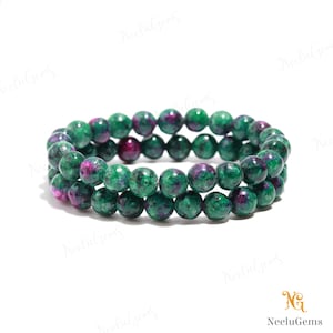 May include: Two stacked bracelets made of green and magenta gemstone beads. The beads are round and have a speckled appearance. The bracelets are displayed on a white background. The image is well-lit and shows the details of the gemstones.