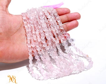 May include: A strand of pale pink rose quartz beads, each bead is round and slightly flattened. The beads are strung on a clear thread and are approximately 8mm in diameter.
