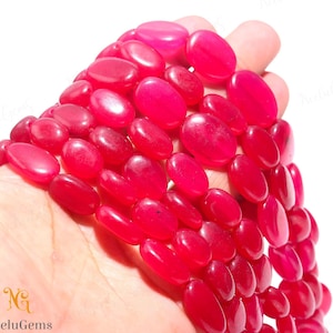 Può includere: Una collana di perline ovali di pietra preziosa rosa brillante. Le perline sono lisce e lucidate e hanno un aspetto leggermente traslucido.