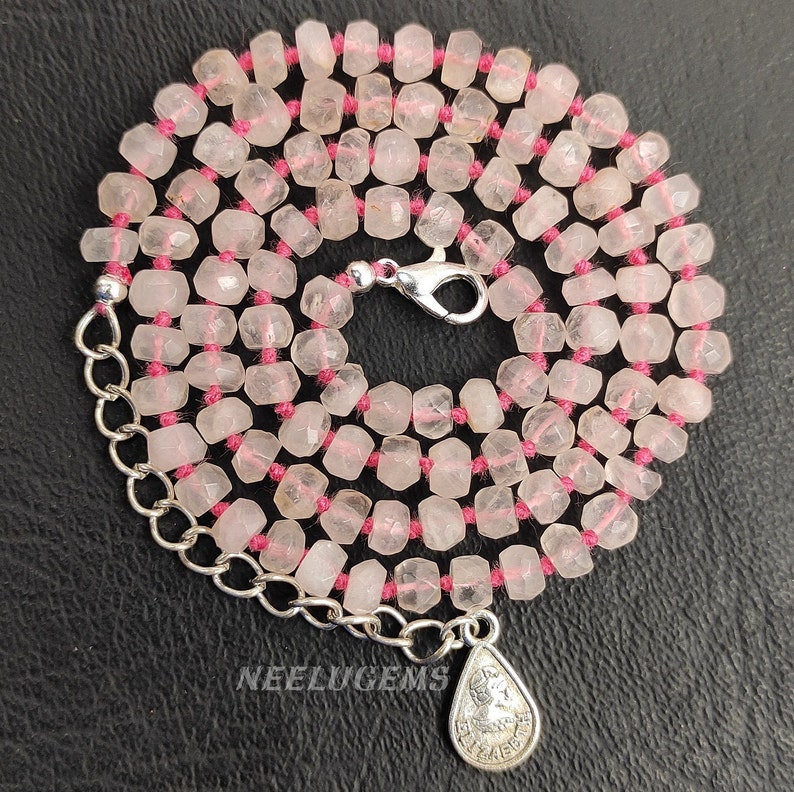 May include: A pink rose quartz beaded necklace with a silver clasp and a silver pendant. The beads are faceted and strung on a pink thread.