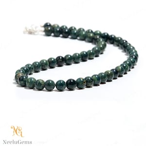 May include: A green and black gemstone bead necklace. The beads are round and have a mottled appearance.