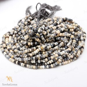 May include: A strand of small, round, white, gray, and black gemstone beads. The beads are approximately 4mm in diameter and have a speckled pattern. The beads are strung on a thin, clear thread.