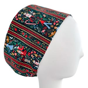 May include: A dark green scrub cap with a festive Christmas pattern. The cap features red stripes and a repeating design of nutcrackers, angels, and holiday elements. The cap is designed to fit comfortably.