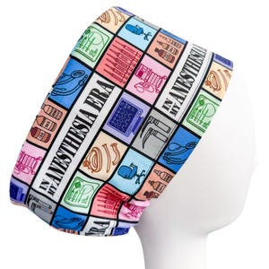 May include: A colorful scrub cap with a repeating pattern of medical equipment and the text "IN MY ANESTHESIA ERA". The cap features squares of various colors, including pink, blue, and yellow, with illustrations of syringes, monitors, and other medical tools.