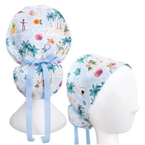 May include: A light blue scrub cap with a tropical island print featuring palm trees, surfers, and hula dancers. The cap has a light blue ribbon tie and is designed to be worn on the head.