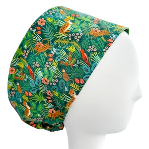 May include: A green scrub cap with a jungle-themed pattern. The fabric features orange tigers, leopards, and red birds amidst a backdrop of green foliage and orange flowers. The cap is designed to fit over the head.