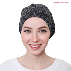 May include: Black and white patterned cap with a cat design. The cap is worn on the head. The text "Example when worn" is in the upper right corner.
