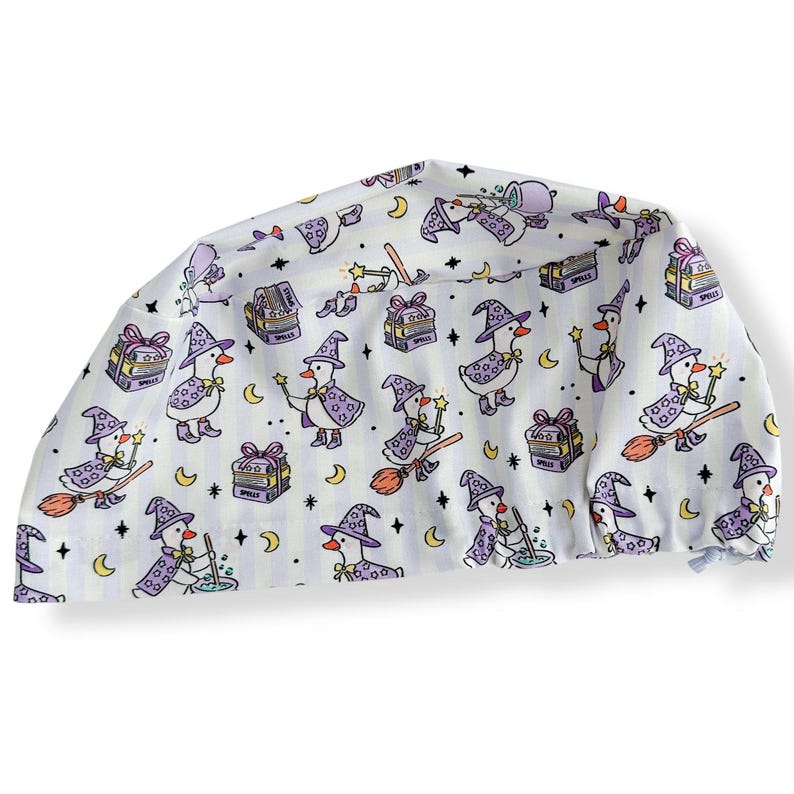 May include: White fabric item with a repeating pattern of cartoon geese dressed as witches, holding wands and riding brooms. The geese are wearing purple hats and capes. The background includes moons, stars, and gift boxes.