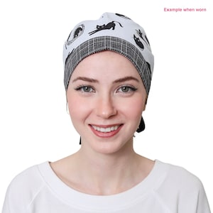 May include: A white cap with a black cat pattern and a black and white checkered band. The cap is tied in the back. The text "Example when worn" is in the upper right corner.
