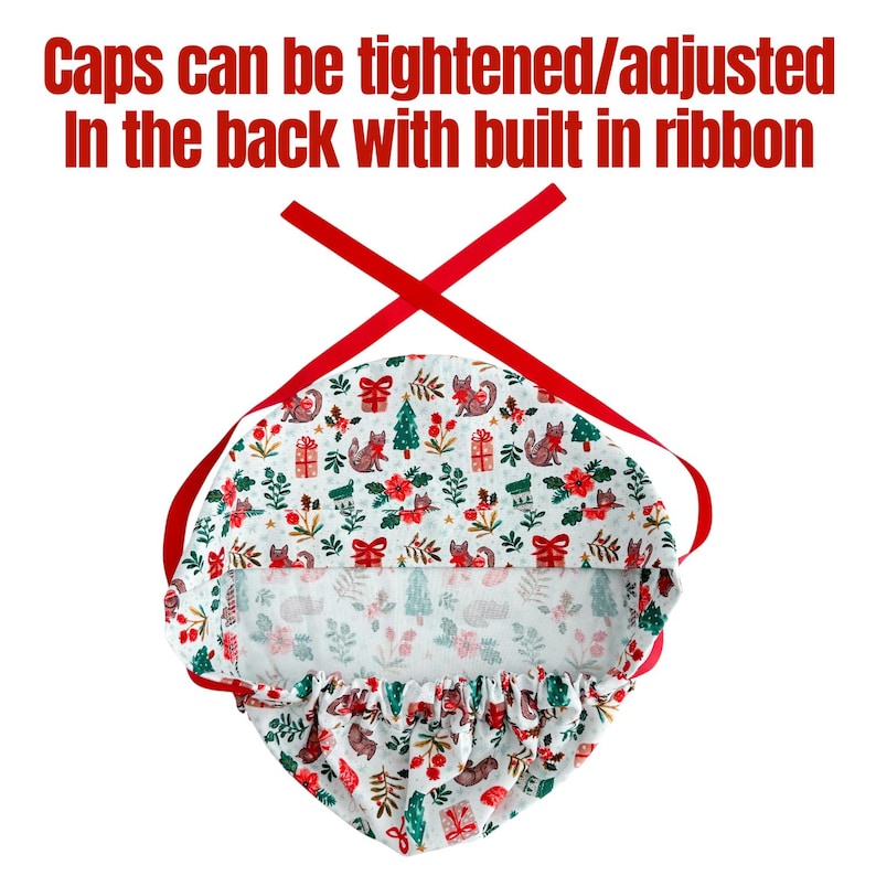 May include: A white patterned cap with a festive design featuring foxes, Christmas trees, and gifts. The cap has a red ribbon for adjustment and the text "Caps can be tightened/adjusted In the back with built in ribbon".