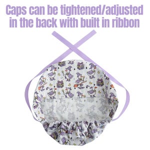 May include: A white patterned cap with a witch duck design, featuring a purple ribbon for adjustment. The cap has a repeating pattern of witch ducks, gift boxes, and moons. The text "Caps can be tightened/adjusted in the back with built in ribbon" is at the top.