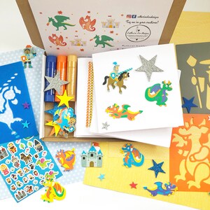 May include: A fantasy-themed craft kit with stencils, stickers, glitter stars, and glue sticks. The kit includes images of dragons, knights, castles, and wizards. The box is open, revealing the contents, with a variety of colours and textures.