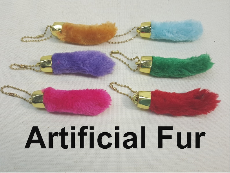 May include: Five faux fur keychains in different colors: orange, purple, green, pink, and red. Each keychain has a gold metal ring and a chain.