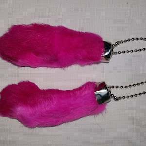 May include: Two pink fuzzy rabbit foot keychains with silver metal rings and chains.