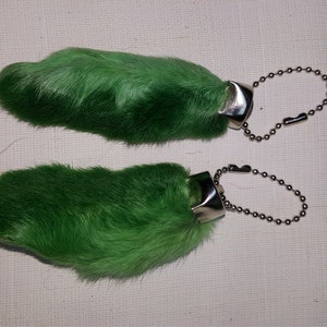 May include: Two green rabbit foot keychains with silver metal rings and chains.