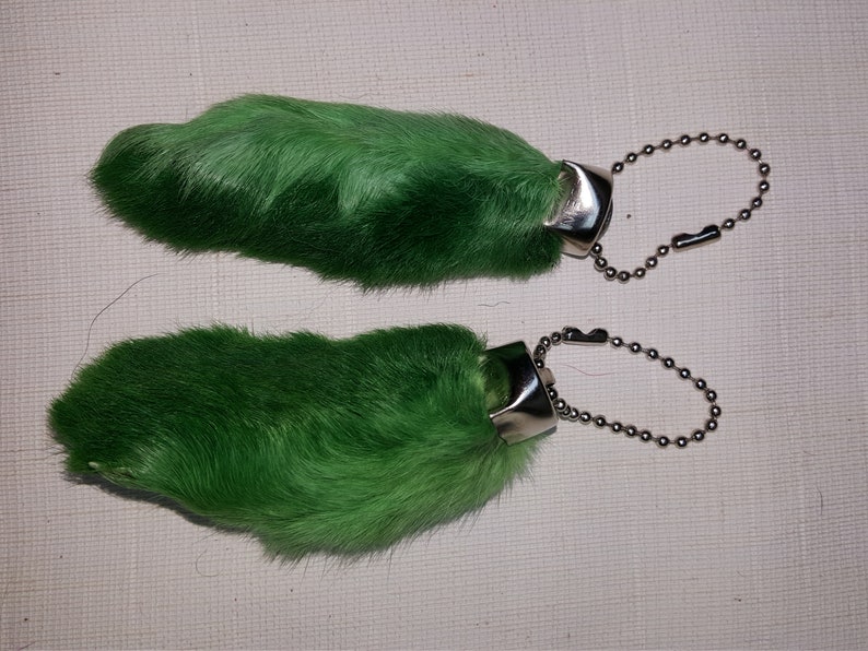 May include: Two green rabbit foot keychains with silver metal rings and chains.