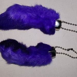 May include: Two purple faux fur rabbit foot keychains with silver metal rings and chains.