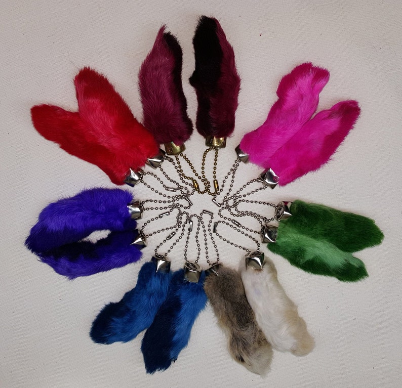 May include: A set of ten colorful faux fur keychains shaped like rabbit feet. Each keychain is attached to a silver chain with a metal ring.