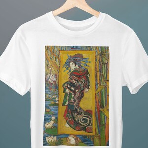 Könnte beinhalten: Ein weißes T-Shirt mit einem farbenfrohen Bild einer Frau in einem Kimono, die in einem Feld mit Seerosen steht. Das Bild ist in einem gelben Rahmen gefasst und von grünem Bambus umgeben.